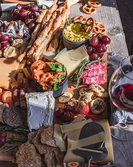 Cheeseboard mit Käse, Crackern, Dip, Weintrauben, Salami und Wein
