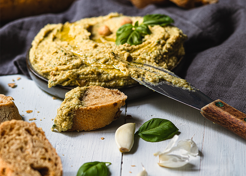 Basilikum Hummus in Schale und Baguette Brot